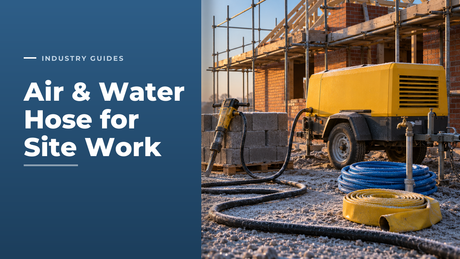 Frosty construction site at sunrise with a yellow towable air compressor feeding black rubber air line hose to a pneumatic breaker, beside a coil of blue braided PVC water hose on a standpipe and a rolled coil of yellow PVC layflat hose