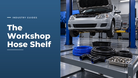 Automotive workshop with a car raised on a two-post lift and a trolley holding coils of blue silicone coolant hose, black rubber radiator and fuel hose, silicone elbows and a tray of worm drive hose clips