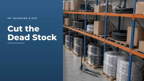 Hose distributor stockroom aisle with orange and blue pallet racking holding coils of black rubber and clear braided PVC hose, some upper bays holding slow-moving part-used coils